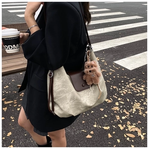Detailed view of large vintage pleated tote bag with dark brown leather flap and bear charm
