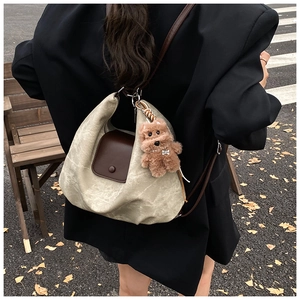 Detail of vintage pleated tote bag with brown flap pocket and cute plush puppy charm
