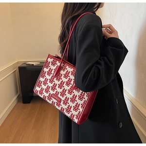 Detail shot of the red festive tote bag showing woven Xi characters and leather straps
