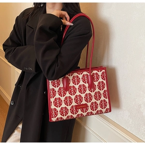 Close-up of red and white jacquard tote bag with traditional Xi pattern and leather handles