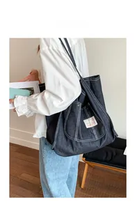 Detail view of large navy denim tote bag with white contrast stitching and logo