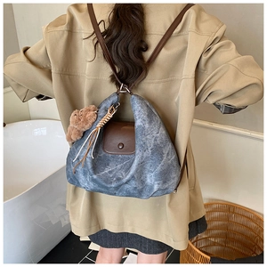 Rear view of model wearing a vintage blue pleated backpack with brown leather accents