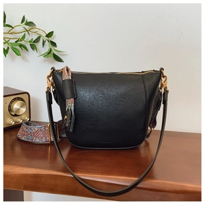 Close-up of black leather bucket bag featuring a colorful Bohemian style wide strap
