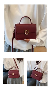 Detail of burgundy lychee grain leather handbag with stylish golden U-shaped metal lock