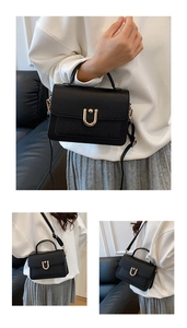 Macro detail of black pebble leather square bag with gold U-shaped metal lock and strap