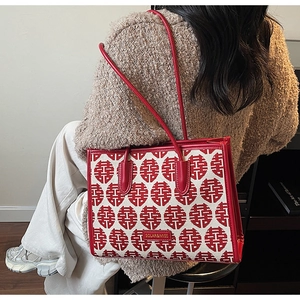 Detailed close-up of a festive beige tote bag with red traditional patterns and leather straps