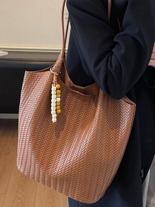 Brown woven leather tote bag with wooden bead charm for women shown on a model