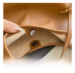 Macro detail of the magnetic snap closure on a brown pebble leather bucket bag