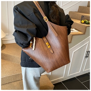 Detailed shot of large brown woven tote bag with wooden beads on adjustable strap