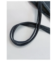 Detailed close-up of dark blue denim tote strap featuring white double stitching craft