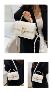 Detail view of white lychee pattern leather handbag with unique U-shaped gold metal lock