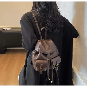 Vista dettagliata di un mini zaino in pelle marrone scuro con fibbie in metallo oro