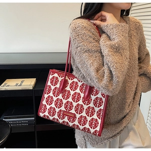 Detail of red and white tote bag with Double Happiness print held by a model