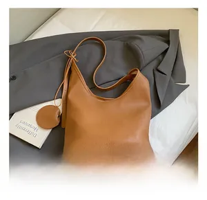 Detail of a brown lychee pattern bucket bag on a grey blazer with round coin purse
