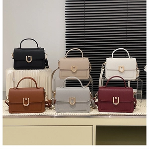 Close-up of six textured leather crossbody bags with U-shaped gold metal buckles