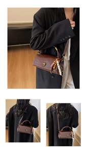 Detail of vintage brown leather handbag featuring gold metal clasp and colorful beaded charm