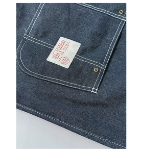 Detailed close-up of dark denim pocket with white double stitching and retro label