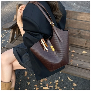 Detail of dark brown woven shoulder bag with golden lock and beaded tassel accessory