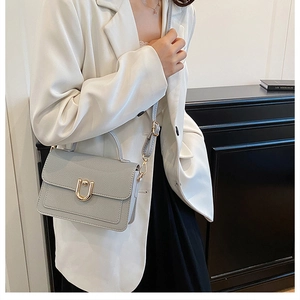 Detail of light grey pebble leather handbag with gold U-shaped buckle and adjustable strap
