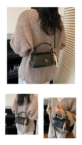 Detail of black retro handbag with gold twist lock and ethnic style colorful bead charm