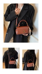Detail view of brown vintage handbag with golden twist lock and bohemian bead tassel charm