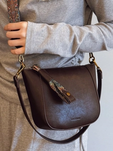 Brown leather bucket bag with geometric wide strap and embossed logo detail
