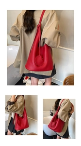Detail of red lychee grain leather hobo bag with round charm and spacious design