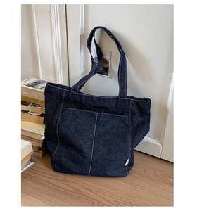 Détail du sac cabas en denim bleu foncé avec surpiqûres blanches et poche externe
