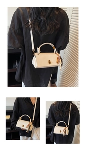 Detailed macro view of cream faux leather handbag featuring golden lock and ethnic tassel
