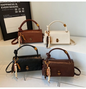 Group of vintage style leather handbags with beaded tassels on display stands