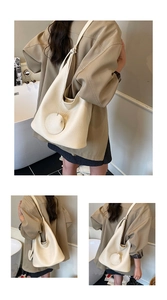Detail view of cream bucket bag with lychee texture and round leather pendant