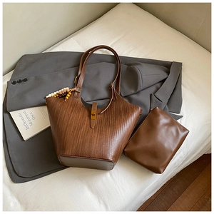 Detail of brown woven tote bag with matching leather pouch and bronze metal fastener