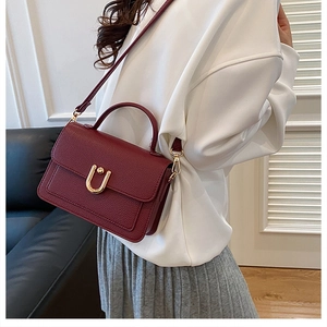 Close-up of wine red lychee pattern leather handbag with gold U-shaped metal buckle