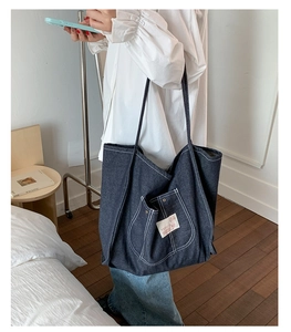 Detail of navy blue denim tote bag with contrast stitching and shoulder strap for students