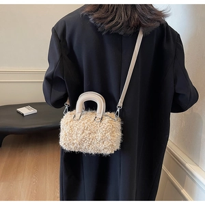 Close-up of beige plush faux fur Boston bag styled with a chic black winter coat