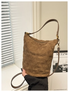 Détail d'un sac seau en daim marron avec surpiqûres en losange et fermeture éclair dorée