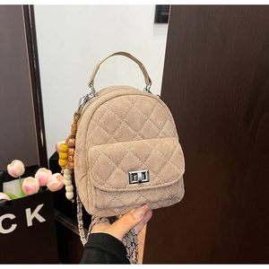 Détail d'un mini sac à dos matelassé kaki avec chaîne argentée et charm de perles