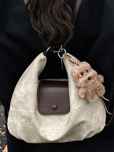 Minimalist beige pleated crescent tote bag with brown leather flap and dog charm accessory