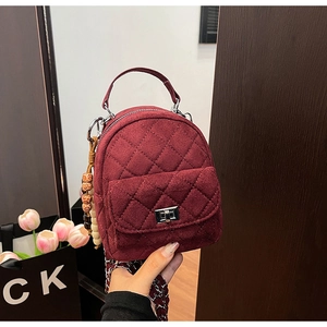 Détail du sac à dos matelassé en velours bordeaux avec fermoir argenté et charm perlé