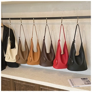 Detailed display of six minimalist hobo bags in various colors on a luxury retail rack