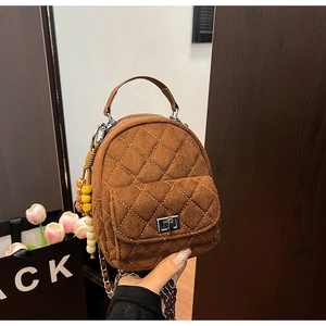 Détail d'un mini sac matelassé en daim marron avec fermoir tournant argenté et gland en bois