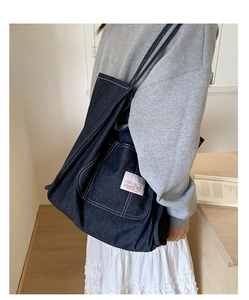 Detailed close-up of dark blue denim tote bag with white contrast stitching and logo