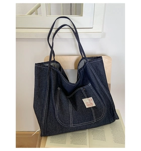 Detail of deep blue denim tote bag with contrast stitching and vintage pocket label