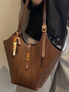 Chic coffee brown tote bag with woven leather texture and elegant beaded tassel