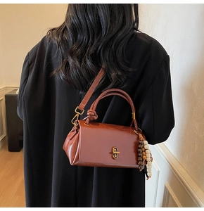 Detail of vintage brown handbag with wooden bead charm on a long black coat