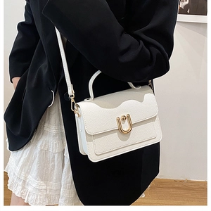 Close-up of white lychee pattern leather handbag with gold U-shaped metal buckle