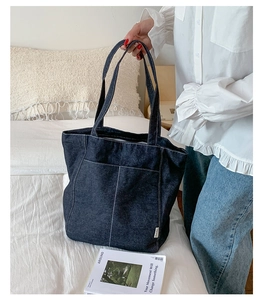 Détail du grand sac cabas en denim bleu foncé avec coutures contrastées et poche avant