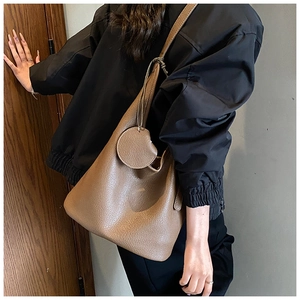 Brown lychee leather bucket bag styled on a shoulder with a black varsity jacket