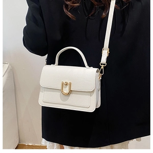 Close-up of white lychee pattern leather handbag with gold U-shaped metal clasp