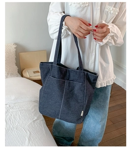 Gros plan d'un cabas en denim bleu foncé avec surpiqûres blanches et poches avant